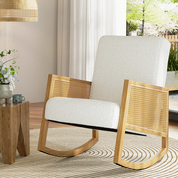 White boucle rocking chair with rattan cane armrests and natural wood frame, in room with rattan pendant lamp and side table
