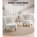 Two white boucle button-tufted wingback chairs with wood legs and gold side table on jute rug, 