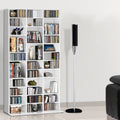 White multi-column CD and DVD media storage shelf loaded with discs and books in living room beside speaker