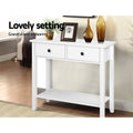 White console table with two drawers in entryway, styled with plant, photo frame and amber vases; text 