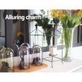 Console top styled with glass bell domes, animal figurines, metal lantern and flower vase; text 