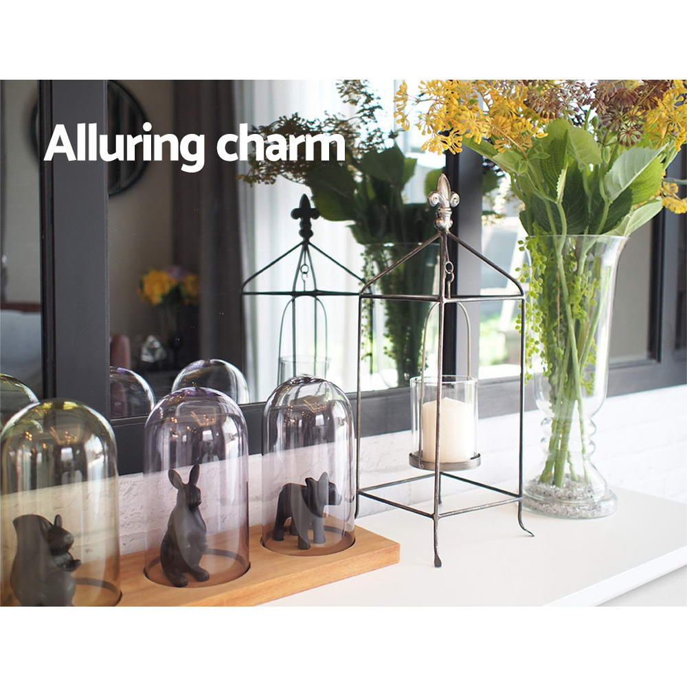 Console top styled with glass bell domes, animal figurines, metal lantern and flower vase; text "Alluring charm"