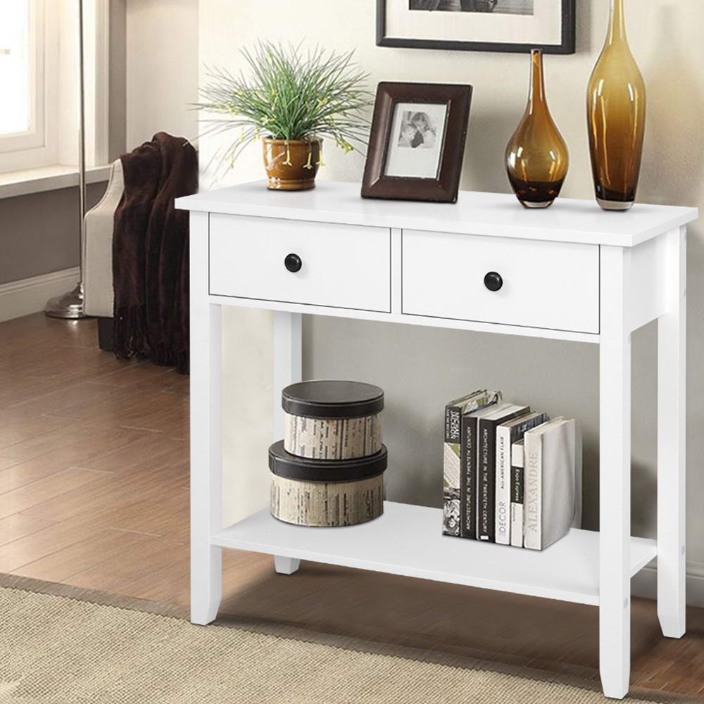 White console table with two drawers, black round knobs and bottom shelf, styled with plant, vases and photo frame