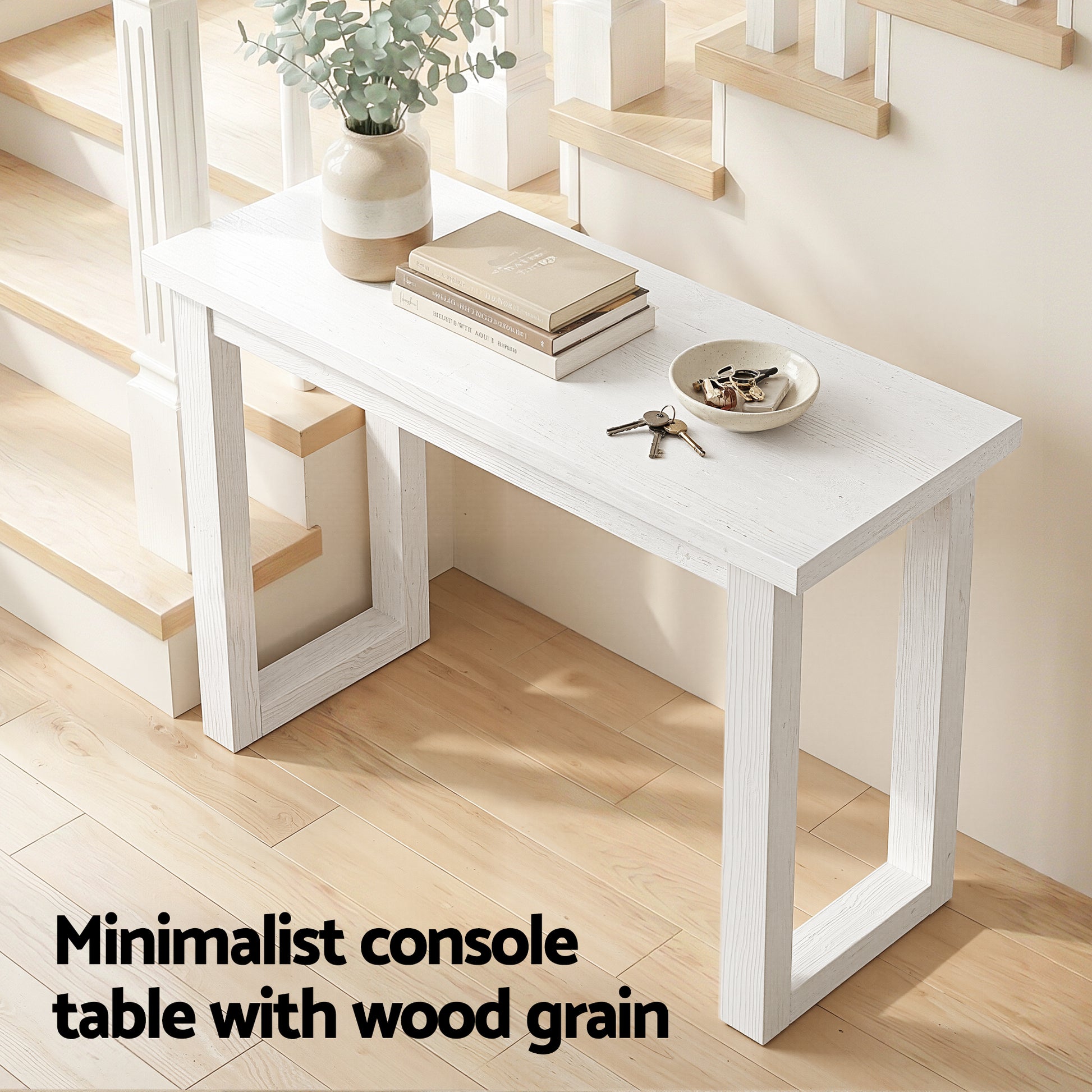 White wood-grain console table in staircase hallway with books and keys, text "Minimalist console table with wood grain"