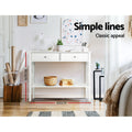 White console table with X-frame sides in room; dimensions 100x80.5cm, styled with cactus and books; text 