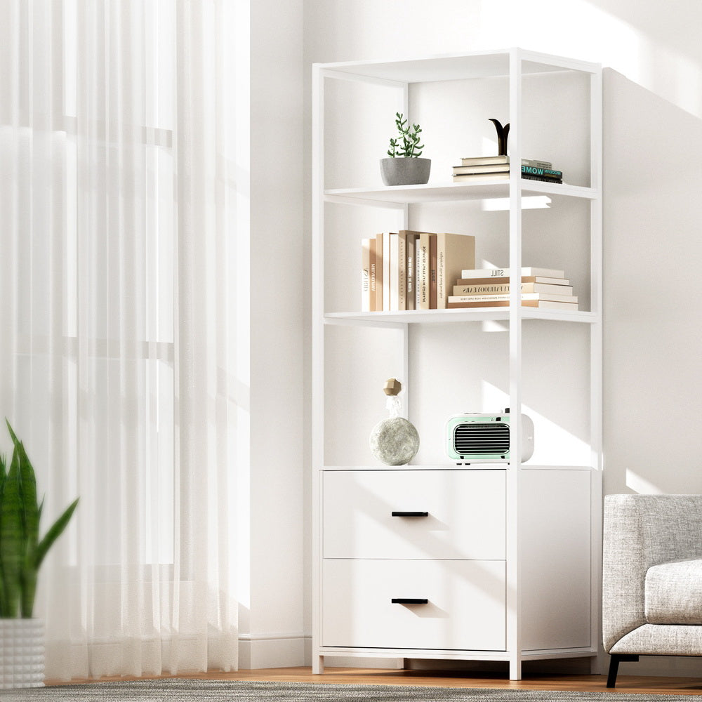 White three-tier display shelf with two drawers styled with books and plants in a bright living room beside a window