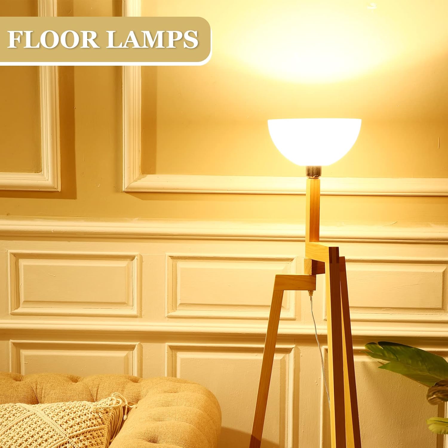 FLOOR LAMPS lifestyle showing white dome shade on wooden tripod floor lamp, glowing warm, tufted ottoman and sofa beside it