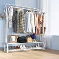 White double-rail garment rack in bedroom with blue striped wall loaded with clothes bags and shoes on bottom shelf