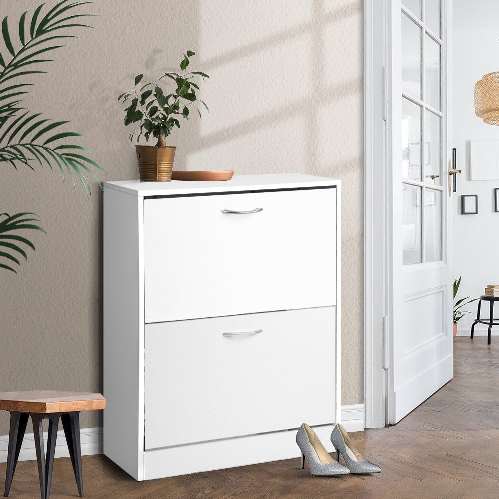 White 2-drawer flip-down shoe cabinet in hallway with plant on top and heels stored below