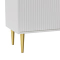 Close-up of white fluted TV unit lower corner showing 2 gold tapered metal legs against white background