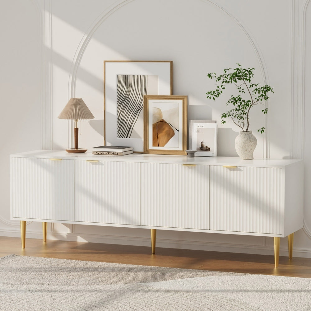 White 180cm TV unit with 4 fluted ribbed doors gold bar handles and gold tapered legs with art and lamp