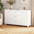 White gloss buffet in living room with neutral wall, eucalyptus vase, books and wooden bird on top, plant and armchair beside