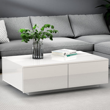 White high-gloss coffee table with two front drawers in living room setting with grey sofa behind