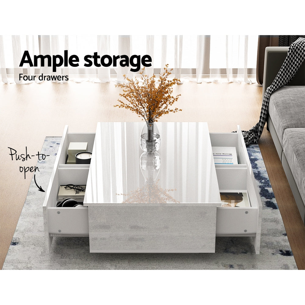 White gloss coffee table with four push-to-open drawers all open showing storage in living room