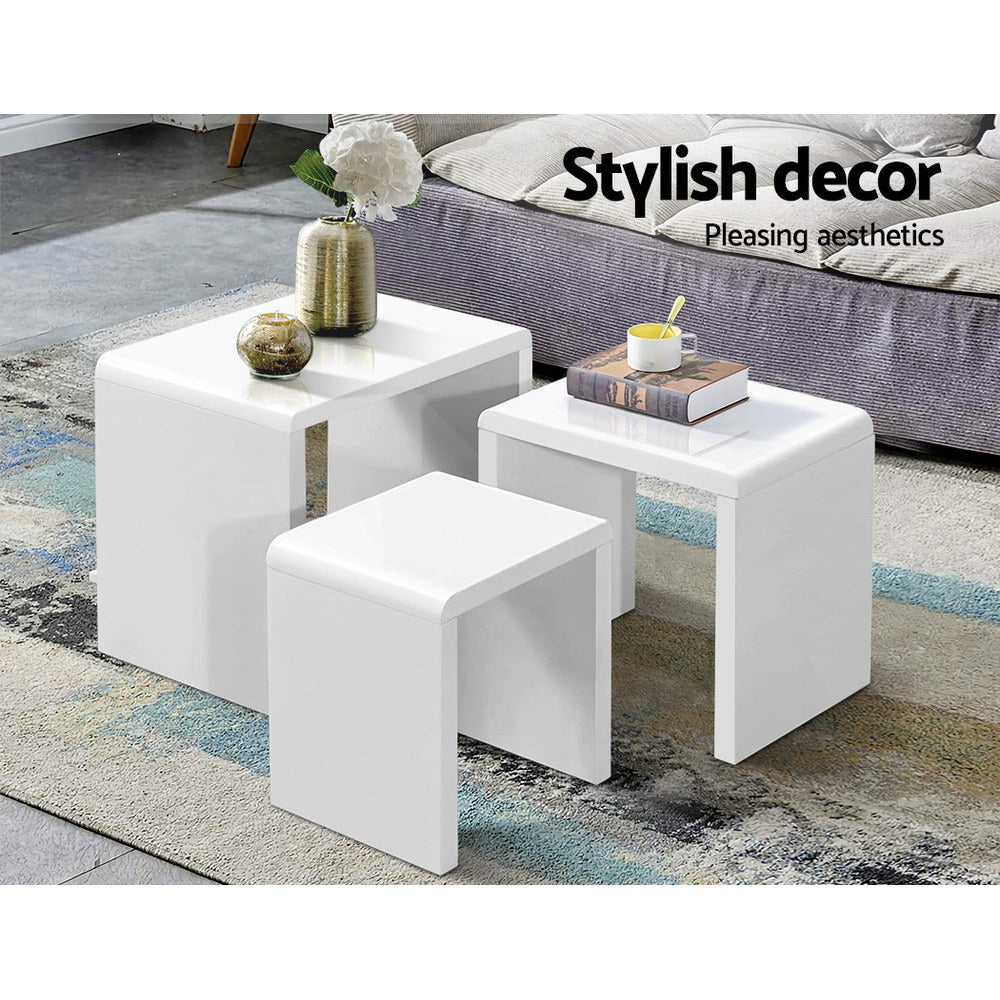 Three white gloss nesting tables beside a grey sofa on a patterned rug, text reads Stylish decor Pleasing aesthetics