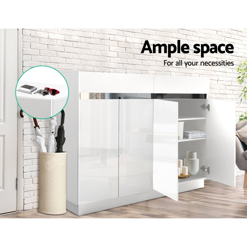 White gloss 3-door shoe cabinet in hallway setting with one door open showing shelves against brick wall