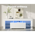 White glossy LED TV unit 130cm pleasant ambience lifestyle with blue LED vase and Walter Finance book