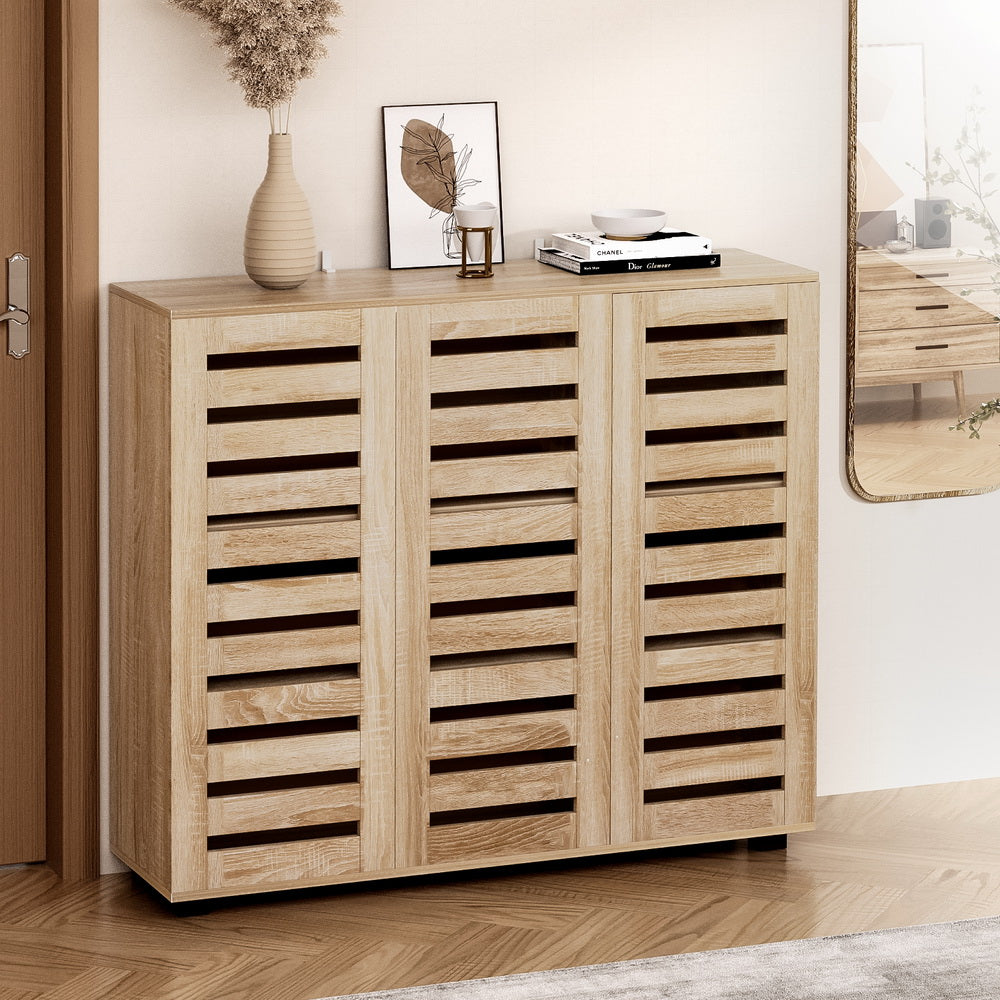 White hall tree entryway unit with coat hooks holding scarves and jackets above open shoe cubbies