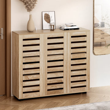 White hall tree entryway unit with coat hooks holding scarves and jackets above open shoe cubbies