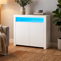 White LED sideboard in living room with blue LED strip lit, vase, books and bowl on top, armchair and plant in background