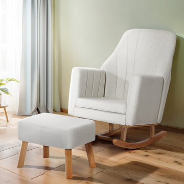 White linen rocking chair with cube ottoman, channel-stitched backrest and oak runners, green wall and wood floor setting