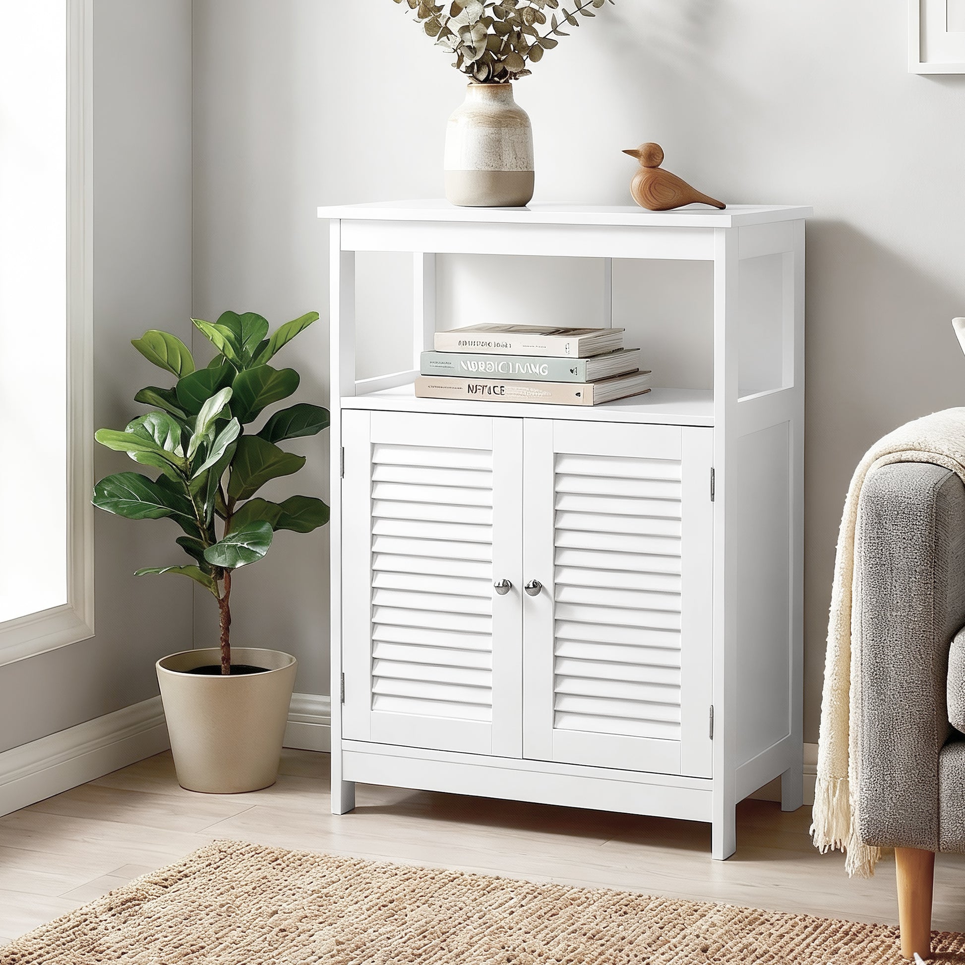 White louvred sideboard in living room with books on open shelf, top styled with vase and eucalyptus, fiddle-leaf fig beside
