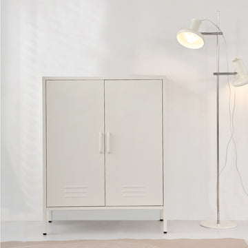 White metal two-door locker cabinet with centre handles and vent slots on base frame in room with white floor lamp