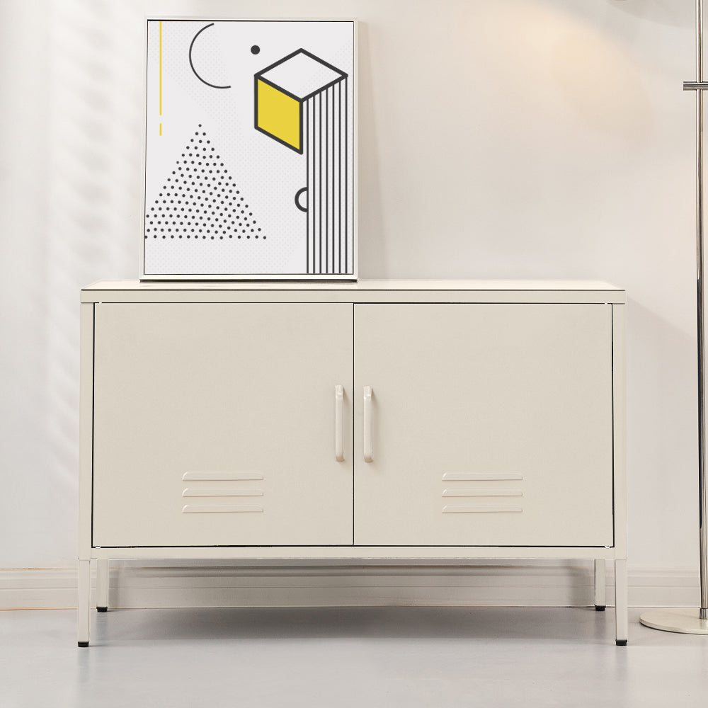 White metal two-door locker cabinet with vent slots on thin legs in living room setting with geometric art print on top