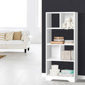 White tall asymmetric open bookcase styled with stuffed rabbit and storage boxes against dark wall in living room
