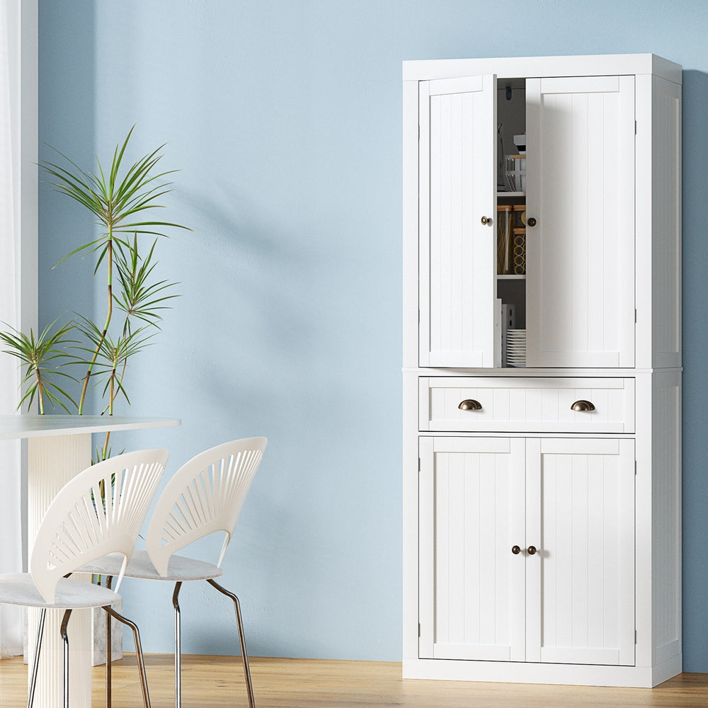 Tall white pantry cabinet in dining room, upper door open showing shelves, middle drawer with cup pulls, lower doors closed