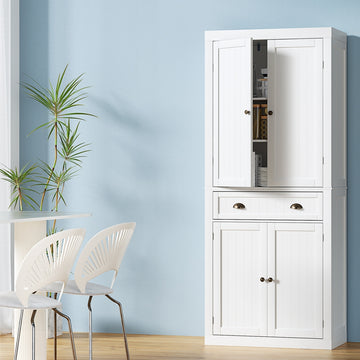 Tall white pantry cabinet in dining room, upper door open showing shelves, middle drawer with cup pulls, lower doors closed