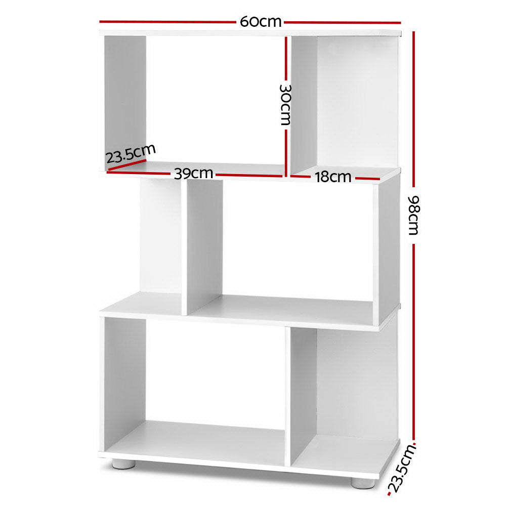 White S-shaped 3-tier display shelf styled with plant, books and cushions against dark feature wall with white sofa visible
