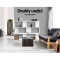 Two white S-shaped display shelves placed side by side as room divider in open living area; text reads Doubly useful