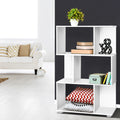 White S-shaped 3-tier shelf beside dark wall styled with plant and books, red chevron cushion in base, white sofa visible