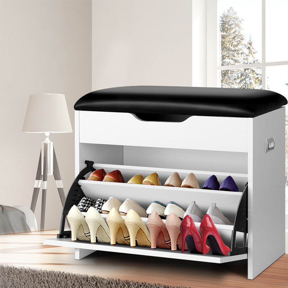 White shoe bench with black PU leather cushion, two tiers deployed loaded with heels in living room with floor lamp