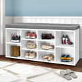 White shoe bench grey cushion with boots heels ballet flats and sneakers in hallway lifestyle with blue wall wainscot