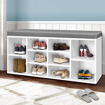 White shoe bench grey cushion with boots heels ballet flats and sneakers in hallway lifestyle with blue wall wainscot
