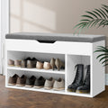 White shoe bench with grey cushion open lower shelves loaded with heels oxfords and tall boot nook on herringbone floor