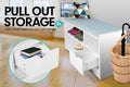 White shoe bench with pull-out drawer open holding books, shoes on upper shelf, wicker basket nearby