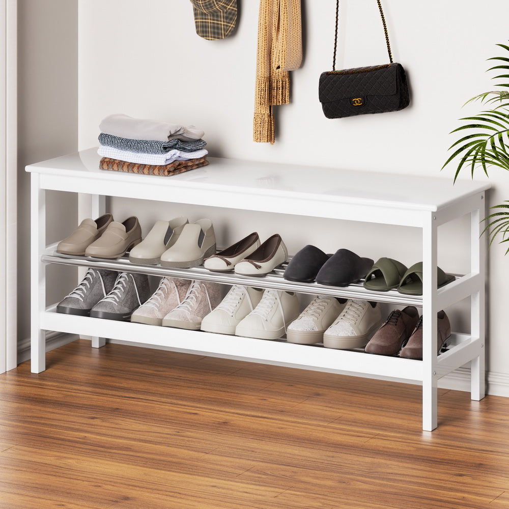 White shoe storage bench with two stainless steel slatted shelves loaded with shoes in entryway room