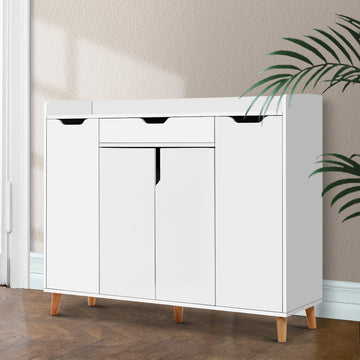 White shoe cabinet with top drawer three lower hinged doors and natural wood cone legs in hallway with herringbone floor