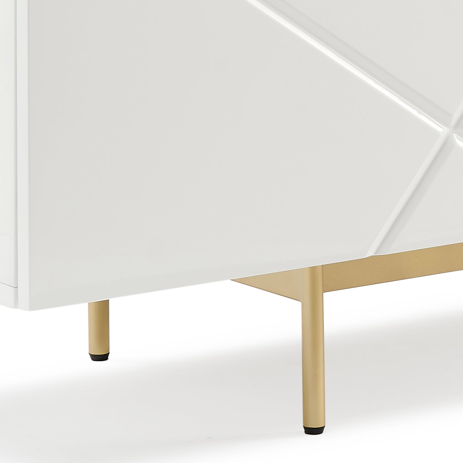 Close-up of white gloss sideboard lower corner with geometric faceted door and brass-finish metal legs with rubber feet