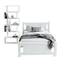 White single bed frame with panel headboard and footboard beside white zigzag bookshelf, on white background