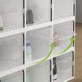 Stack of 12 white shoe storage boxes with one front door open showing drop-front mechanism with green arrows