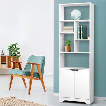 White tall bookcase with open shelves and two-door cabinet in living room lifestyle setting with armchair