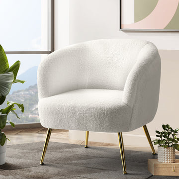 White teddy fabric barrel armchair with splayed gold metal legs in lifestyle room with large tropical plant and abstract art