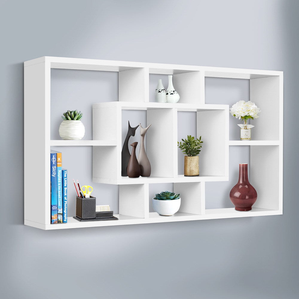 White wall-mounted display shelf on grey wall styled with vases, succulents, books and decorative ornaments