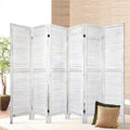 White-washed 6-panel louvered wood room divider in lifestyle room with ficus tree bamboo wall panel and cushions on cream rug