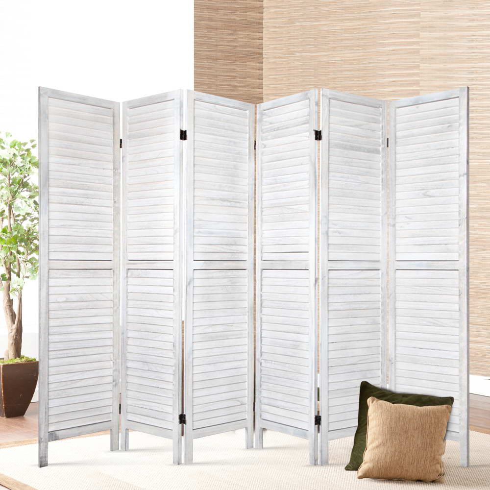 White-washed 6-panel louvered wood room divider in lifestyle room with ficus tree bamboo wall panel and cushions on cream rug