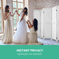 White-washed louvered wood room divider in dressing room with bride in white gown and bridesmaids in front of brick wall